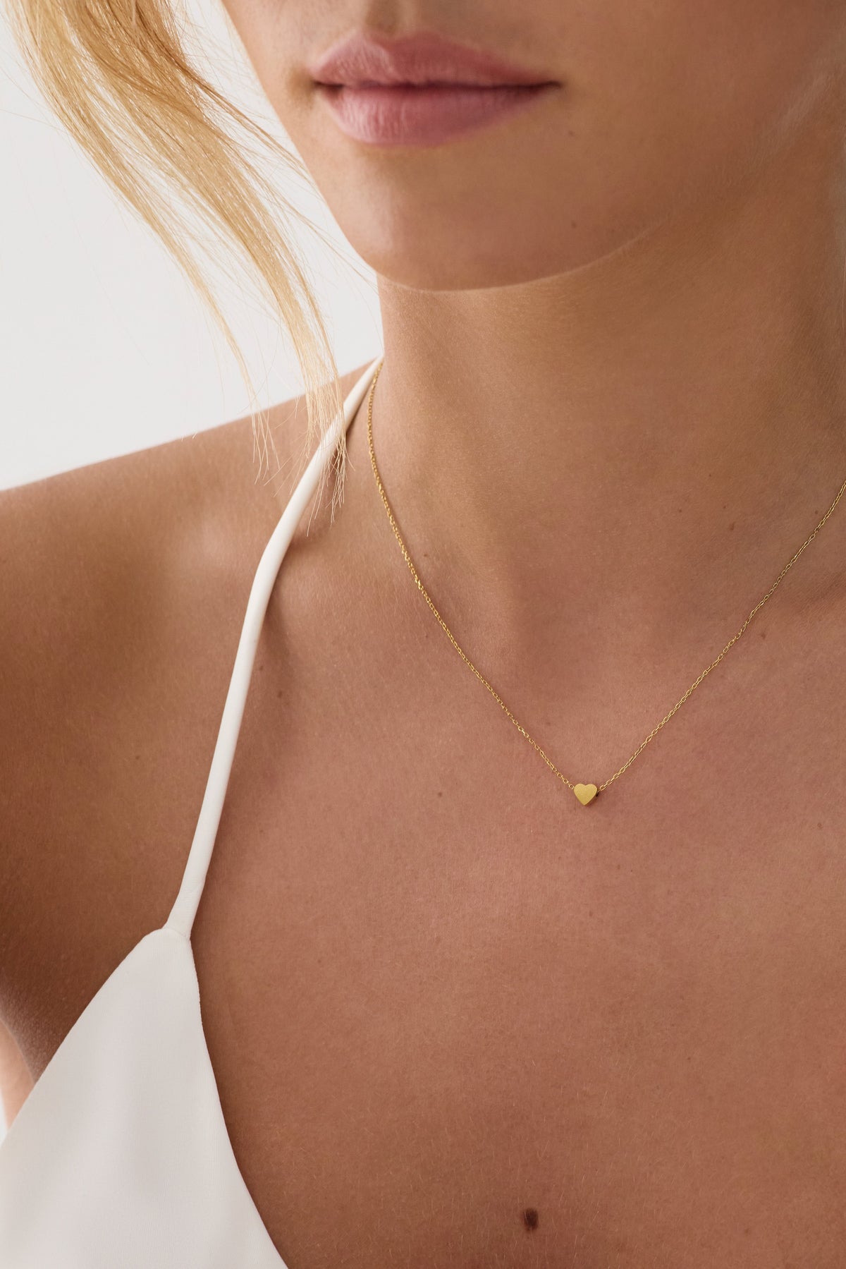 Gold pendant necklace worn close to the skin