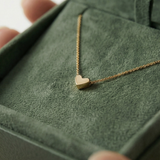 Gold heart necklace on a green jewelry box