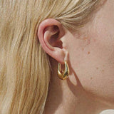 Gold droplet hoop earrings with a gently curved silhouette and smooth, polished finish. Crafted from 18K gold-plated brass, measuring 1 x 0.7 inches. Hypoallergenic, water- and tarnish-resistant—ideal for effortless everyday elegance.