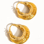 Gold swirl hoop earrings styled on the ear