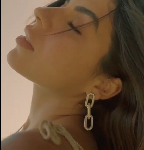 Close-up of a person wearing a chain-link earring with a neutral background