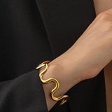 Sculptural statement cuff bracelet crafted from 18K gold-plated stainless steel, featuring a bold, organic wavy silhouette for modern elegance. Hypoallergenic, water- and tarnish-resistant—perfect for adding effortlessly chic style to any outfit.