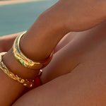 Woman wearing gold jewelry with a cityscape and water in the background