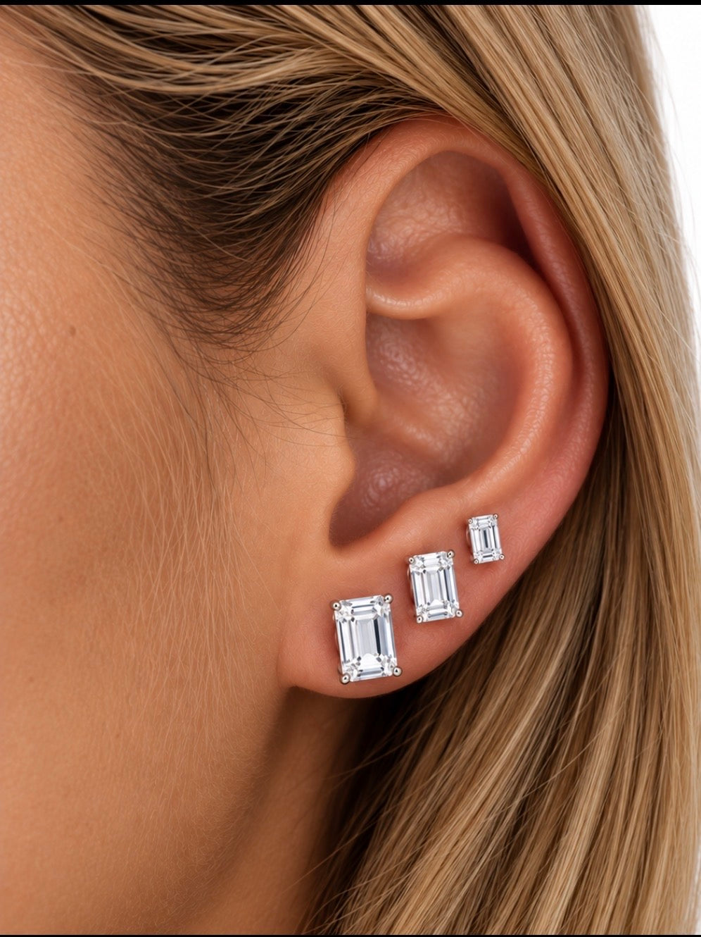 Celeste emerald cut moissanite studs shown on the ear in small, medium and large