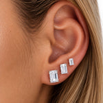 Celeste emerald cut moissanite studs shown on the ear in small, medium and large